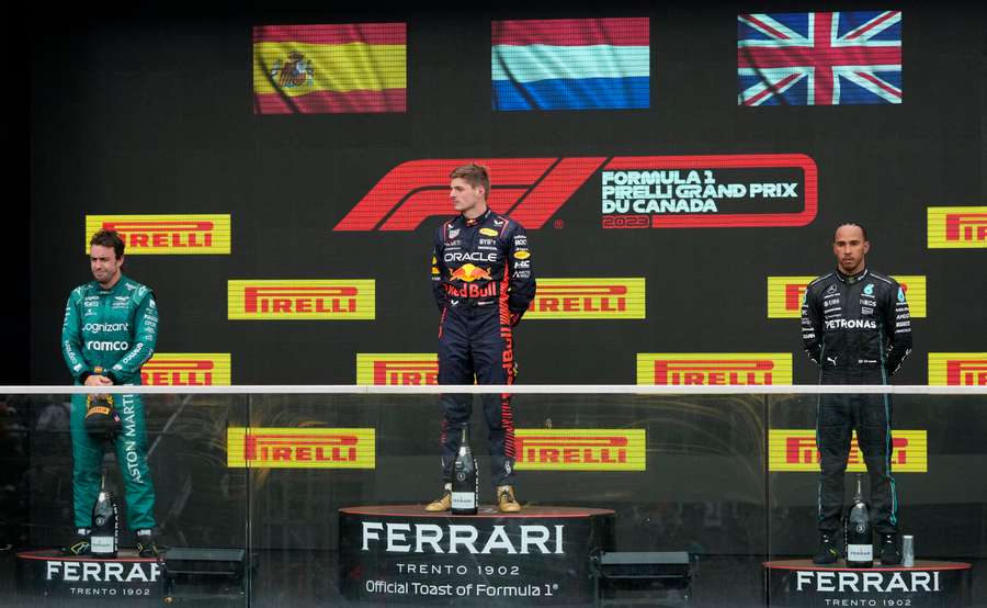 Verstappen celebrates on the podium after winning the race alongside Alonso and Hamilton