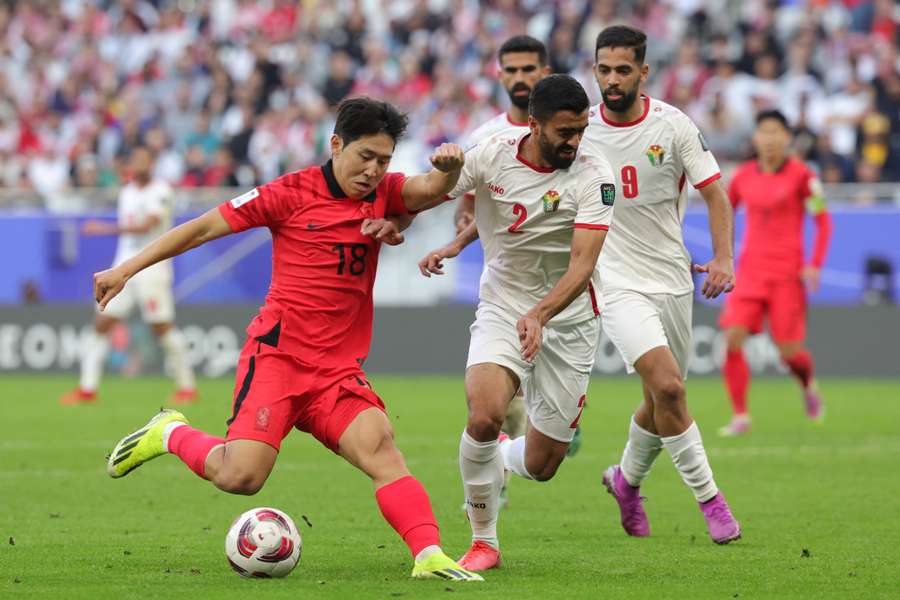 Jordan's Mohammad Abu Hasheesh (R) vies for the ball against South Korea's midfielder Lee Kang-In