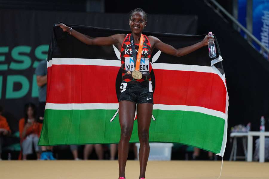 Faith Kipyegon lifts the Kenyan flag after winning her third world title