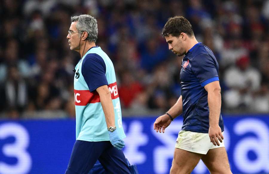 France scrum-half and captain Antoine Dupont (R) leaves the field with the medic