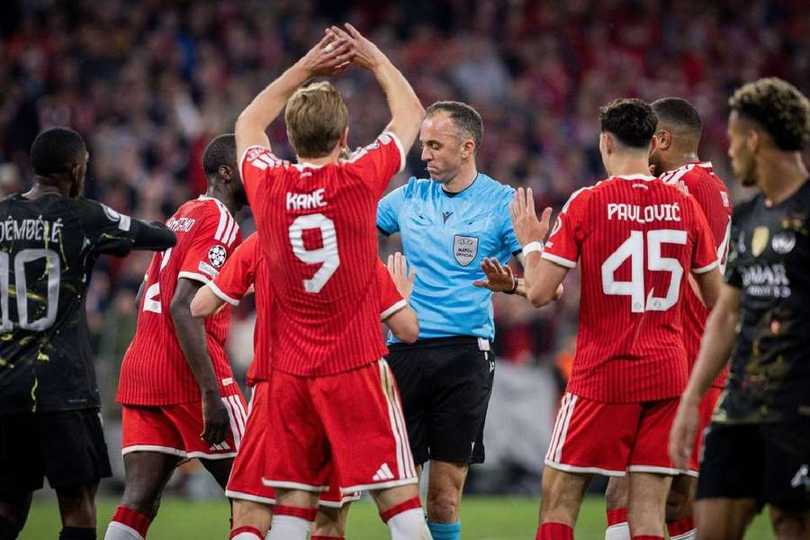 Arbitrul Joao Pinheiro încolțit de jucătorii lui Bayen care cer penalty