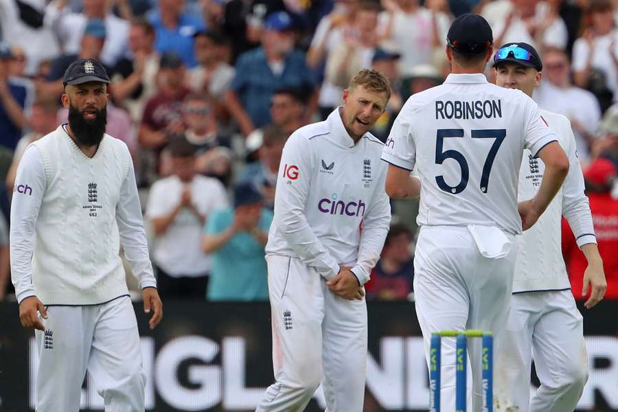 England's Joe Root (C) holds his hand after catching the ball