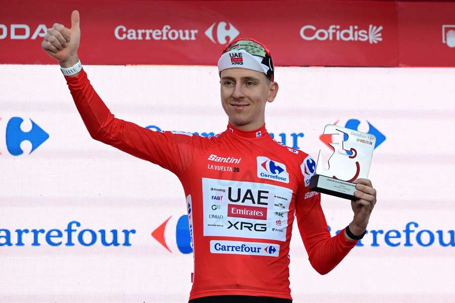 Tadej Pogacar celebrates on the podium after winning the first stage