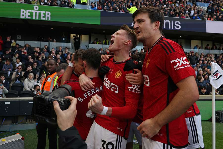 Manchester United's Portuguese midfielder #08 Bruno Fernandes (3L) is mobbed by teammates