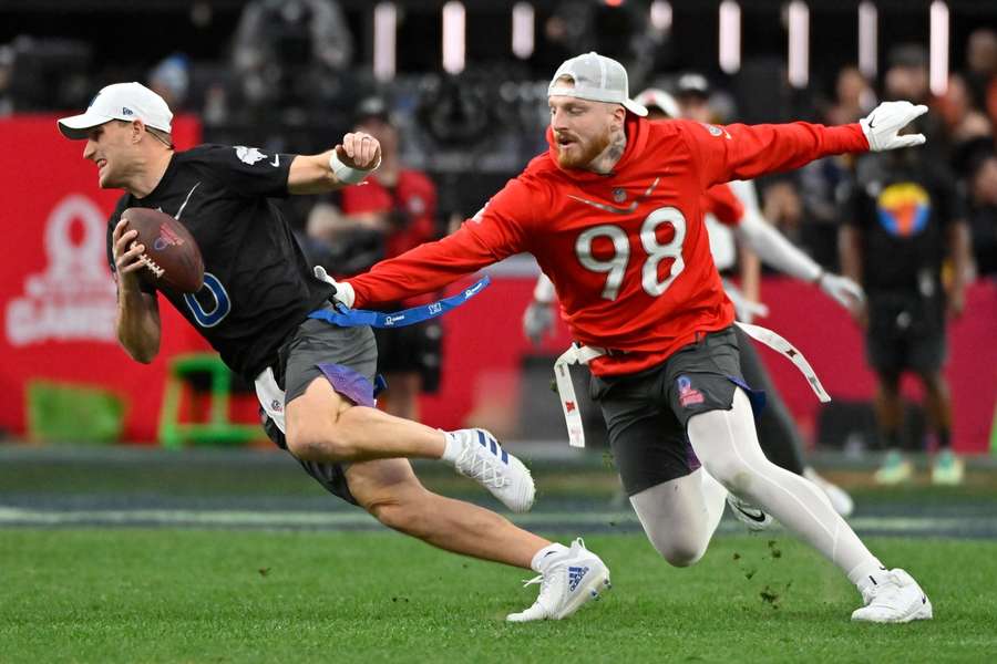 AFC's Maxx Crosby reaches for the flag of NFC's Kirk Cousins during the flag football event