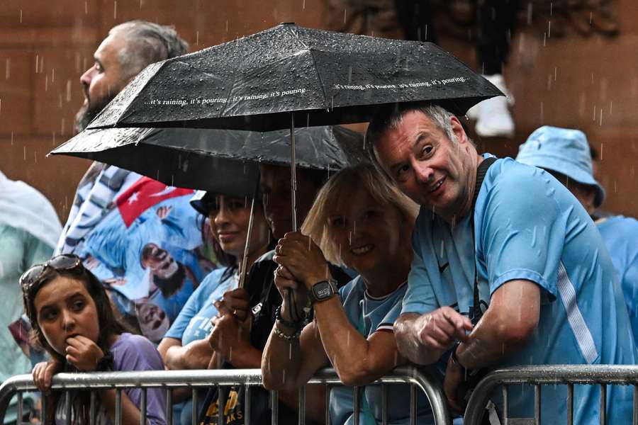 Fans wait patiently in the rain