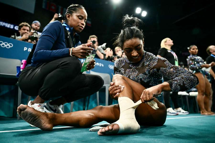 Simone Biles, dos EUA, coloca uma faixa em seu tornozelo esquerdo durante a qualificação feminina da ginástica artística