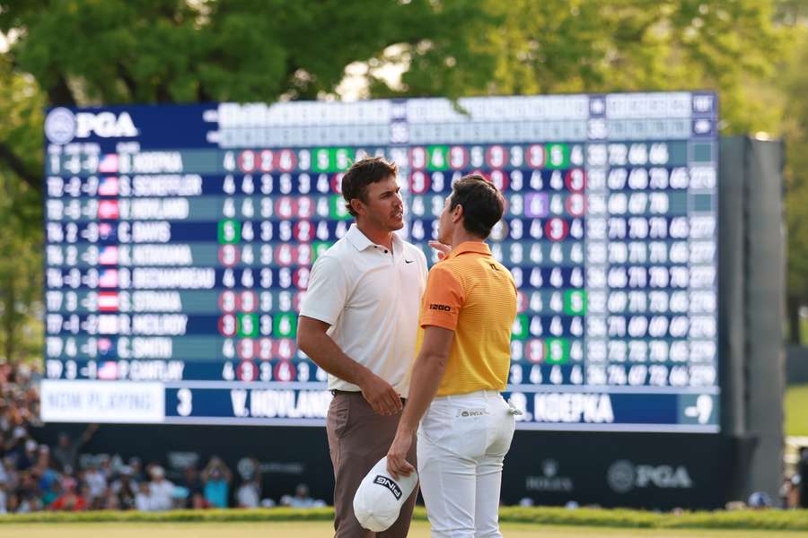 Brooks Koepka of the United States and Viktor Hovland of Norway congratulate each other on the 18th green