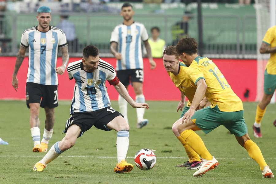 Argentyńczyk Lionel Messi w akcji z Australijczykami Kye Rowlesem i Denisem Genreau