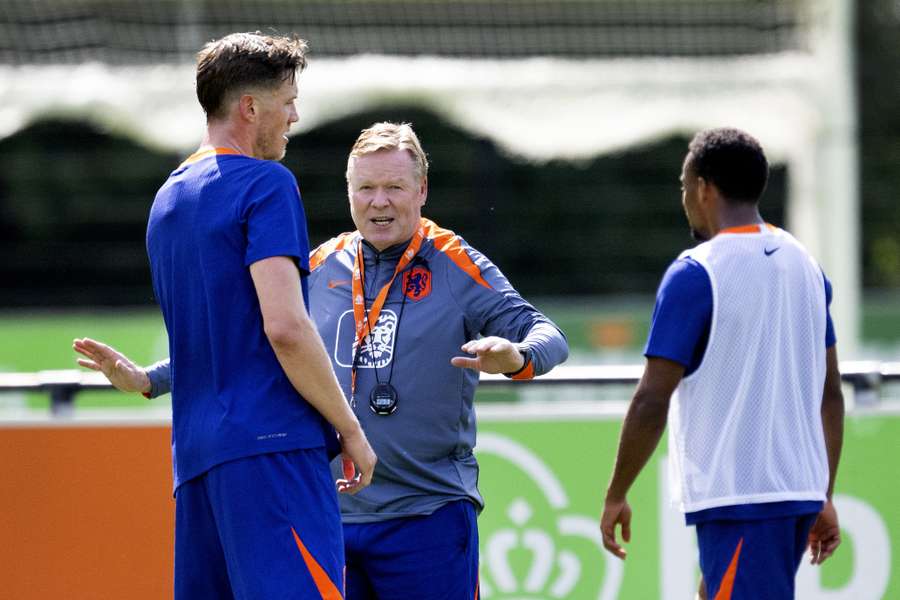 Wout Weghorst (L) and Jurrien Timber (R) speak with Netherlands head coach Ronald Koeman