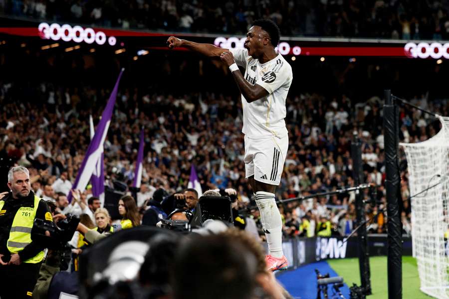 Real Madrid's Vinicius Junior stands atop the hoardings after scoring the winner in the derby