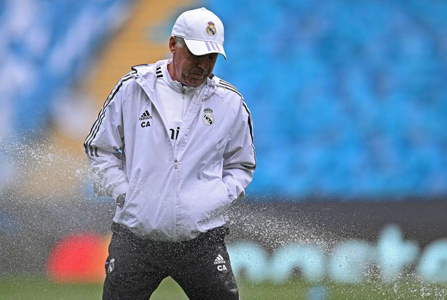 Real Madrid's Italian coach Carlo Ancelotti reacts as he gets caught in a water sprinkler during a team training session at the Etihad Stadium in Manchester