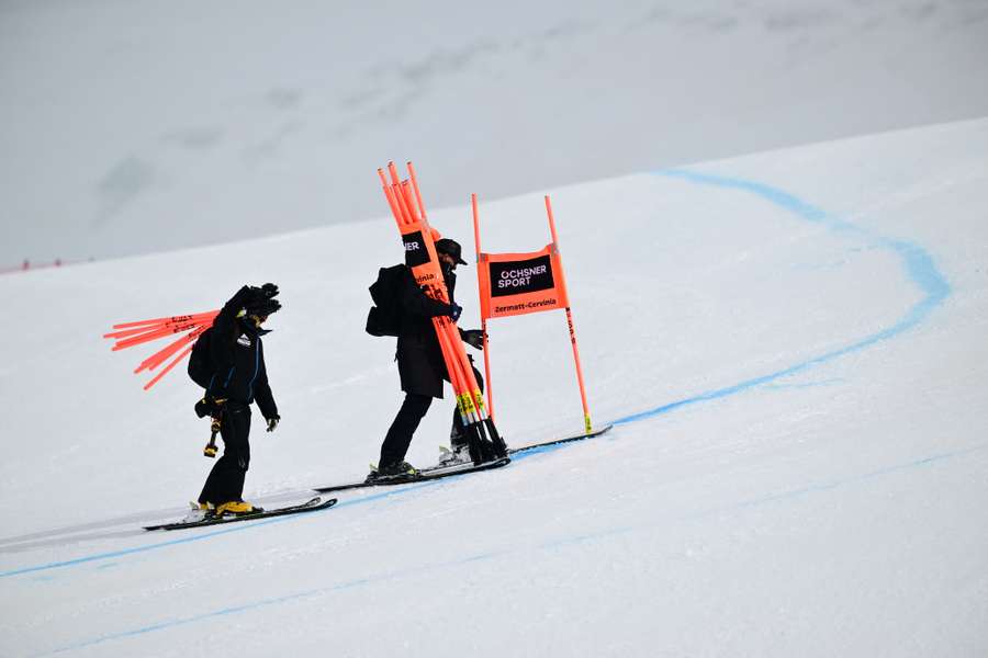 Staff members remove the gates after the women's downhill was cancelled due to bad weather