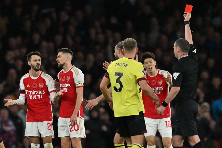 O árbitro inglês Michael Oliver (R) mostra um cartão vermelho ao médio português do Arsenal, Fábio Vieira (21)