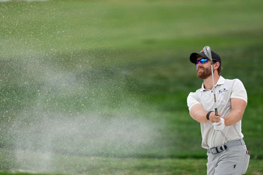 Rodgers plays a shot from the bunker on the 18th hole in Texas