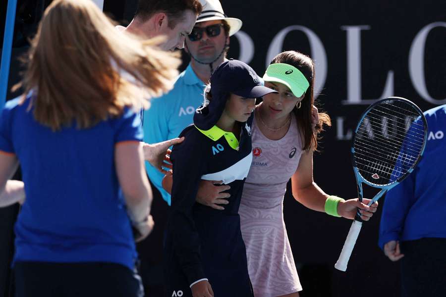Turkey's Zeynep Sonmez helps a ball kid after they collapsed due to heat during her first-round match against Russia's Ekaterina Alexandrova