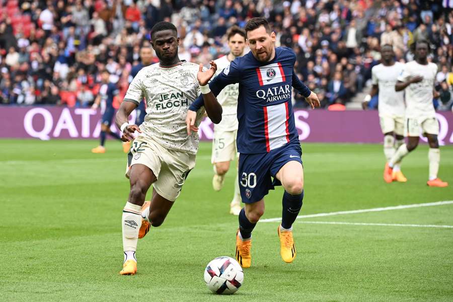 El delantero argentino del París Saint-Germain Lionel Messi (d) lucha por el balón con el defensa camerunés del Lorient Darlin Yongwa.