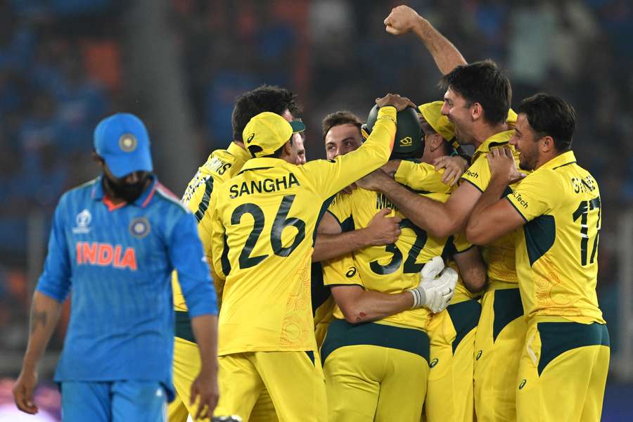 Ravindra Jadeja walks past Australia players celebrating winning the World Cup