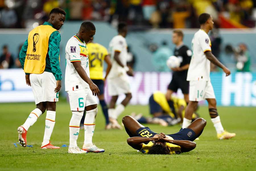 Senegal players walk past a devastated Ecuador player at the end of the game