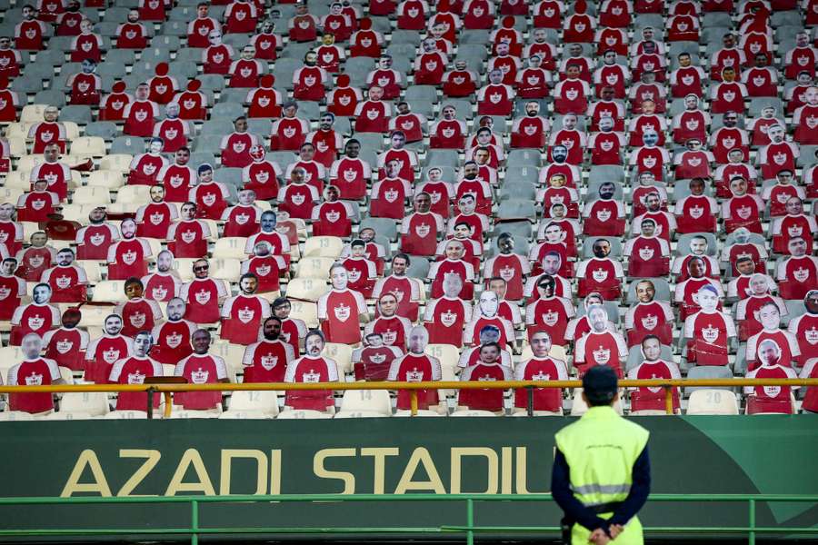 A security official looks at life-size cutouts depicting a crowd of spectators placed on empty seats during the AFC Champions League match