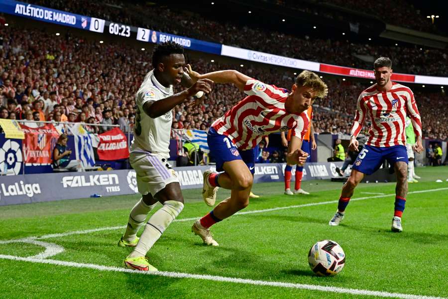 Real Madrid's Brazilian forward Vinicius Junior (L) vies with Atletico Madrid's Spanish midfielder Marcos Llorente