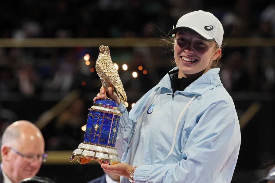 Iga Swiatek celebrates with the Qatar Open trophy after defeating Jessica Pegula in Saturday's final