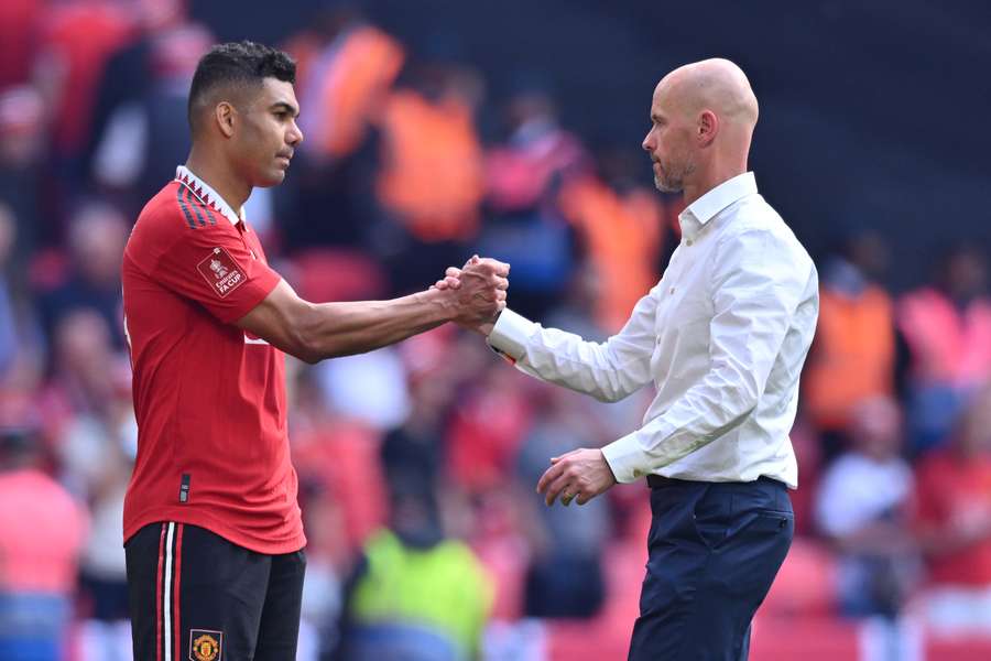 Erik ten Hag (R) consoles Manchester United's Brazilian midfielder Casemiro (L) on the pitch after the English FA Cup final