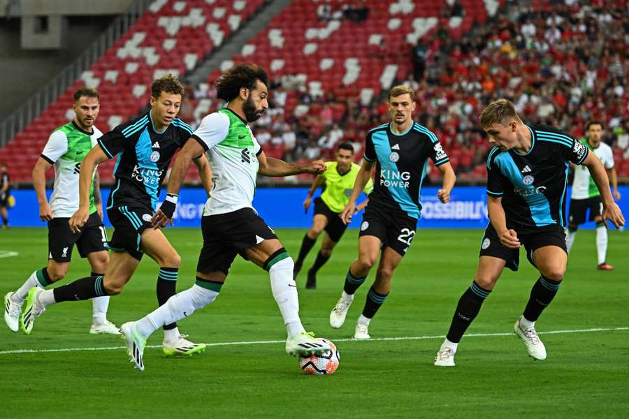 Liverpool forward Mohamed Salah (C) dribbles the ball past Leicester City's players