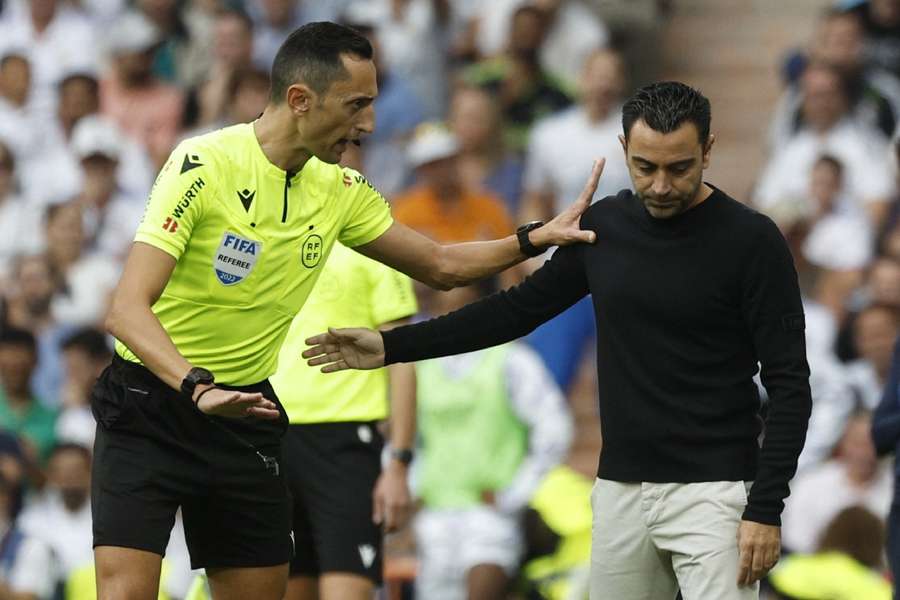 Referee Jose Maria Sanchez Martinez talks to FC Barcelona coach Xavi