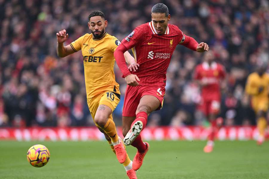 Virgil van Dijk of Liverpool passes the ball whilst under pressure from Matheus Cunha of Wolverhampton Wanderers
