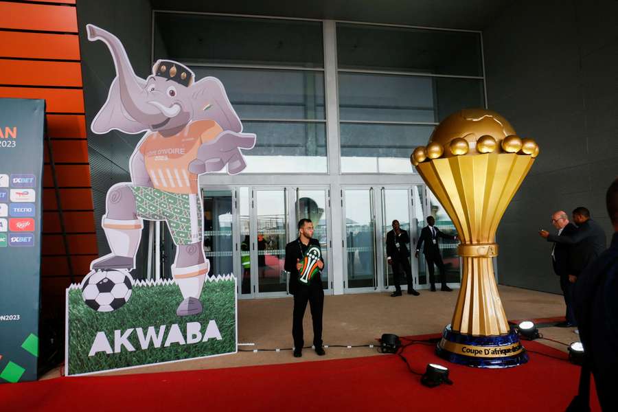 A man stands near the mascot and representation of the nation's African cup during the draw back in October for the finals of the 2023 edition