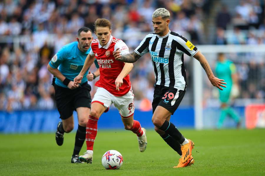 Newcastle United's Brazilian midfielder Bruno Guimaraes (R) fights for the ball with Arsenal's Norwegian midfielder Martin Odegaard