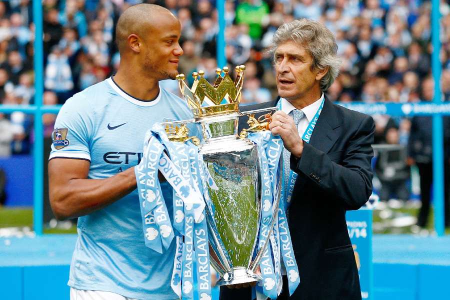 Vincent Kompany holding the 2013/14 Premier League title Vincent Kompany holding the 2013/14 Premier League title