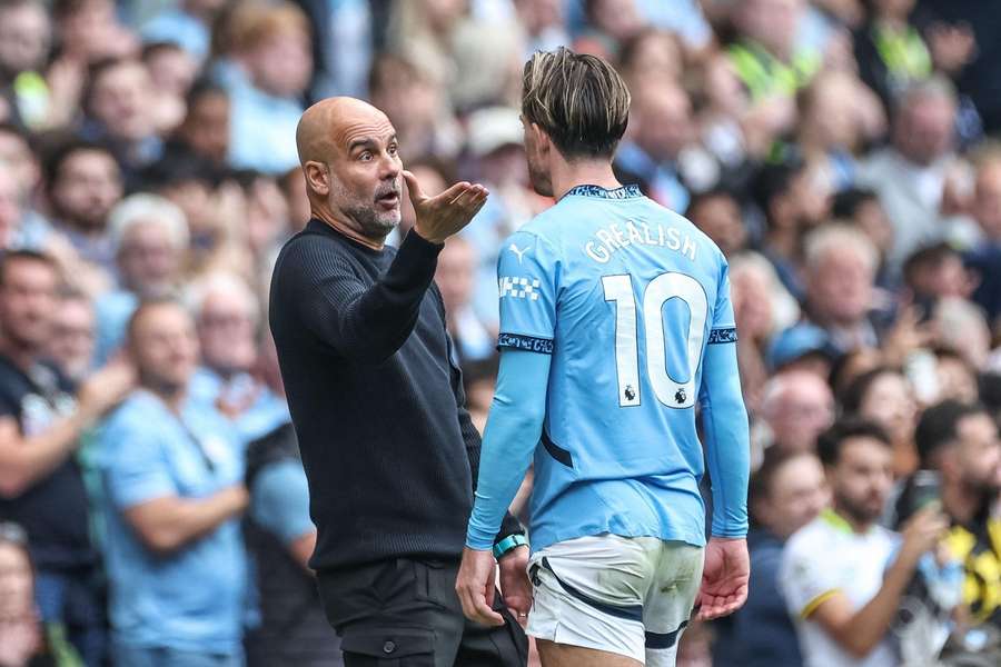 Pep Guardiola manager of Manchester City speaks to Jack Grealish of Manchester City