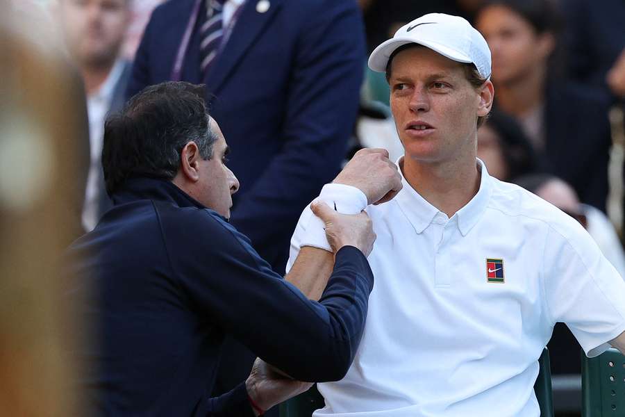 Sinner reacts as he receives medical treatment during his fourth-round match against Dimitrov