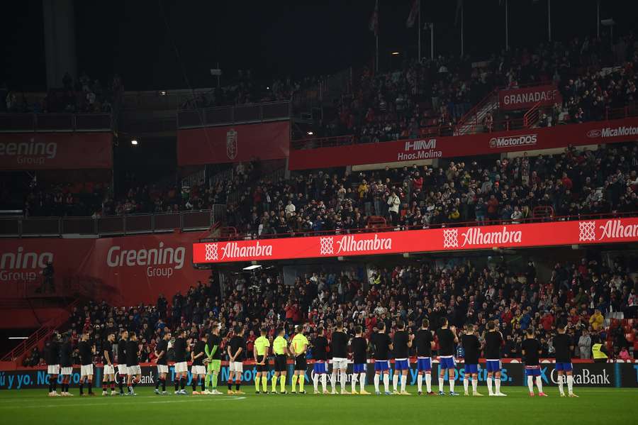 Players stand for a minute of silence to pay respect to late supporter Antonio Trujillo prior to the match between Granada and Athletic Bilbao 