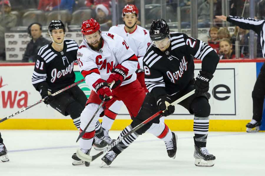 New Jersey's Damon Severson and Carolina's Derek Stepan battle for the puck