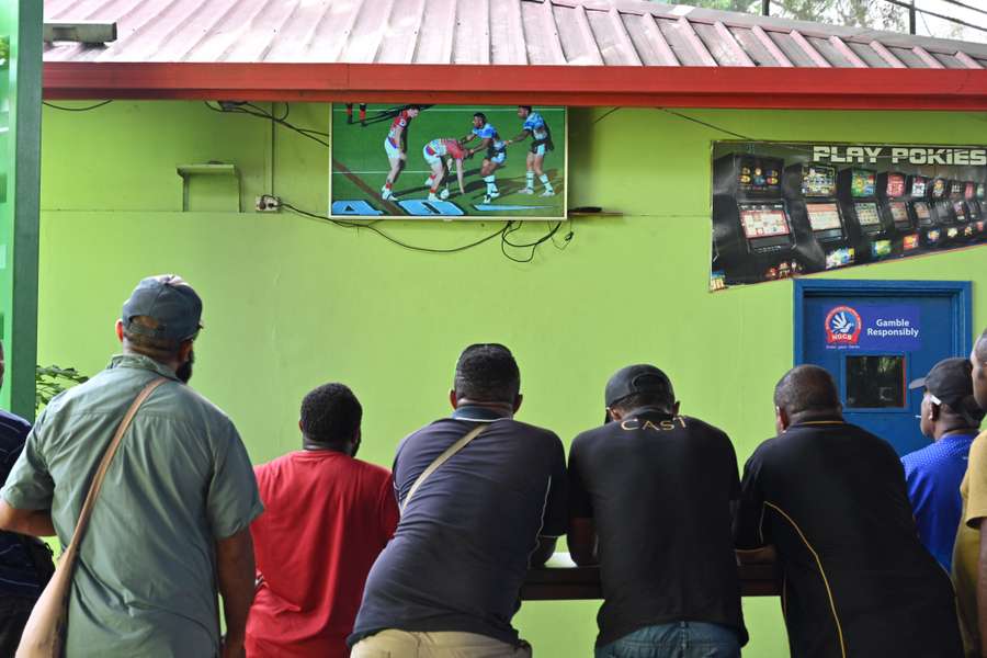 People watch an NRL game on a television at a bar in Port Moresby, PNG.