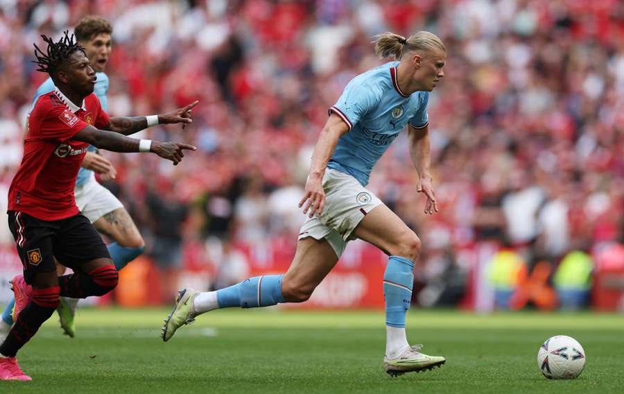 Manchester City striker Erling Haaland (R) runs with the ball