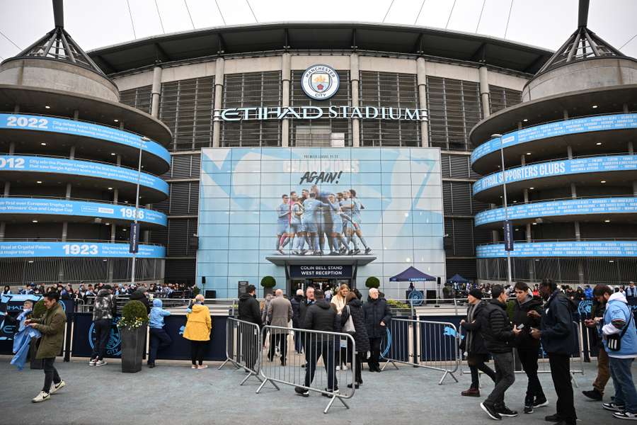 Supporters arrive ahead of the English Premier League football match between Manchester City and Aston Villa at the Etihad Stadium