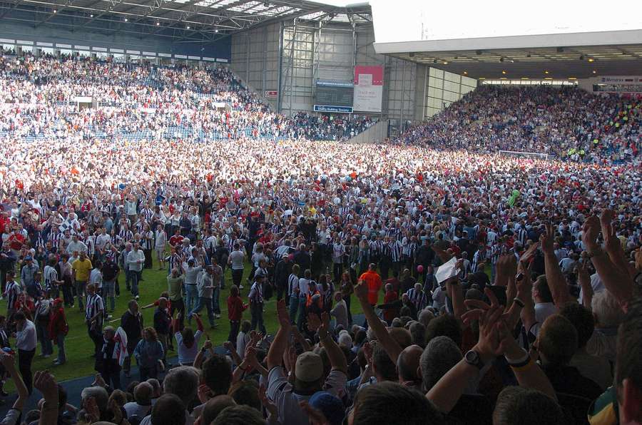 Aficionados del West Bromwich Albion celebran en el campo tras vencer 2-0 al Portsmouth