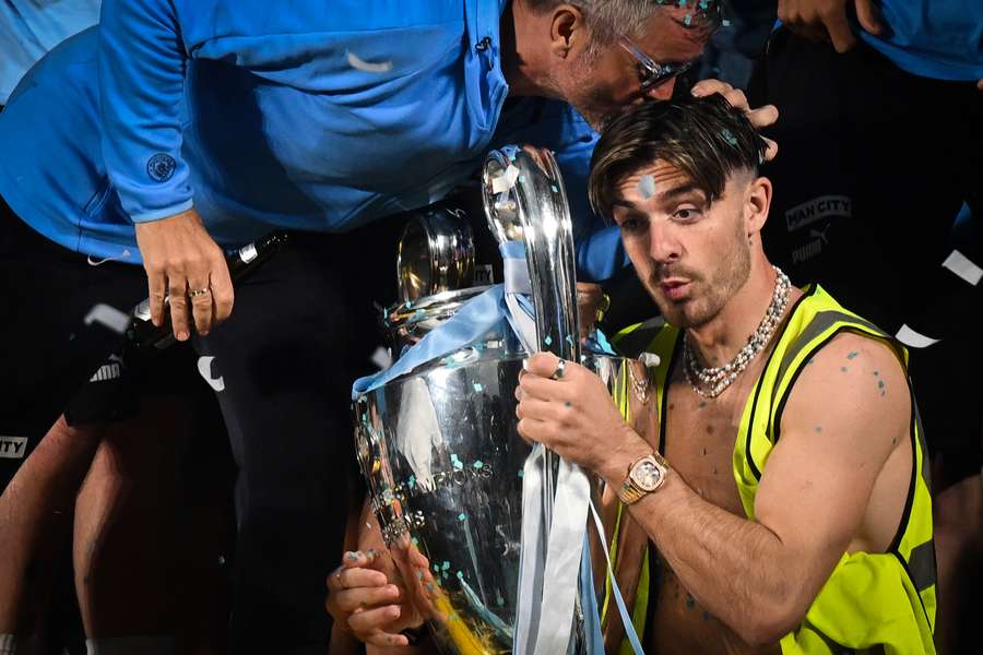 Manchester City midfielder Jack Grealish celebrates with the Champions League trophy on stage following an open-top bus victory parade