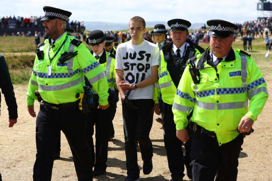 Police officers escort a Just Stop Oil protester off the course