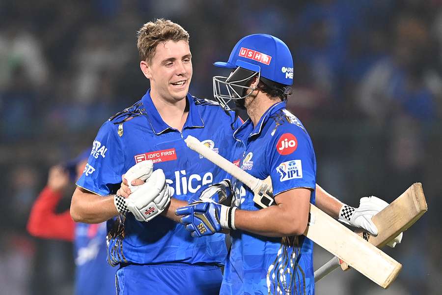 Mumbai Indians' Cameron Green (L) hugs teammate Tim David after their win