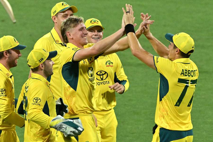 Australia’s paceman Will Sutherland (C) is congratulated by teammates for his first wicket