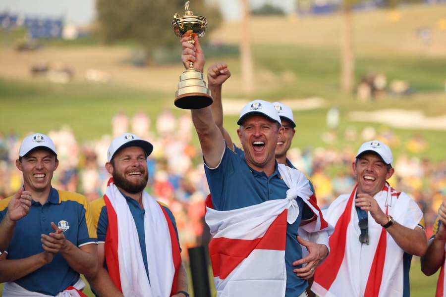 Justin Rose celebrates with the trophy and teammates during the presentation after winning the Ryder Cup