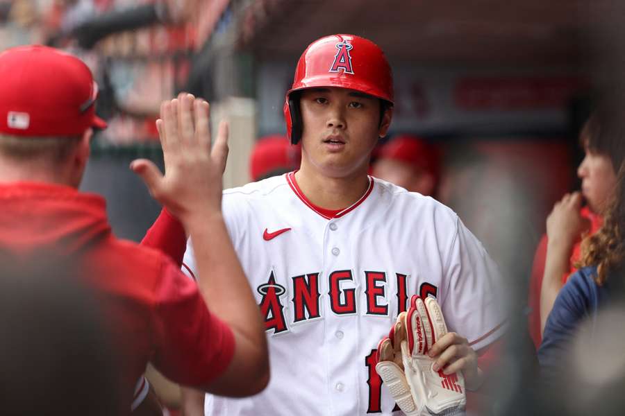 Ohtani is greeted in the dugout after scoring a run during the fifth inning