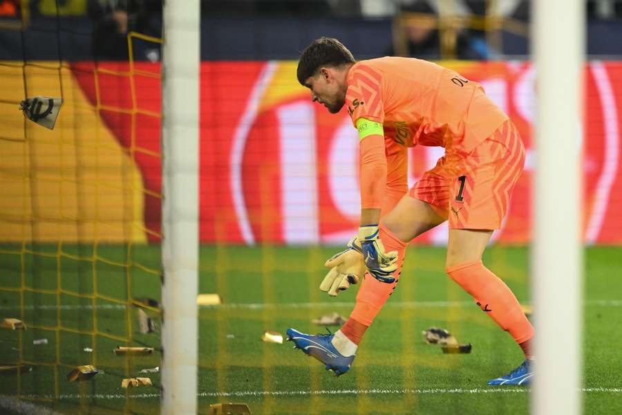 Gregor Kobel cleans up mock-ups of gold bars made of cardboard and thrown on the pitch by Dortmund fans in a protest against Newcastle's owners