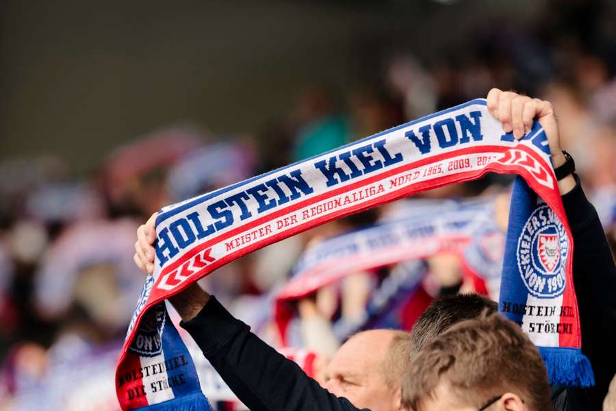 Ein Fan von Holstein Kiel streckt einen Schal in die Höhe.