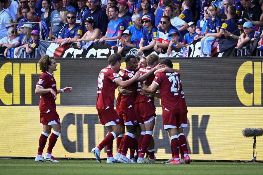 Arminia Bielefeld bejubelt den Treffer zum 2:0 – Bei den Kieler Fans herrscht Enttäuschung.